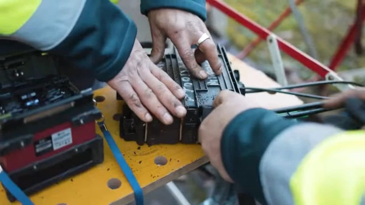 Soudeuse à fibre optique posée sur le chantier, préparation d'une épissure par un technicien